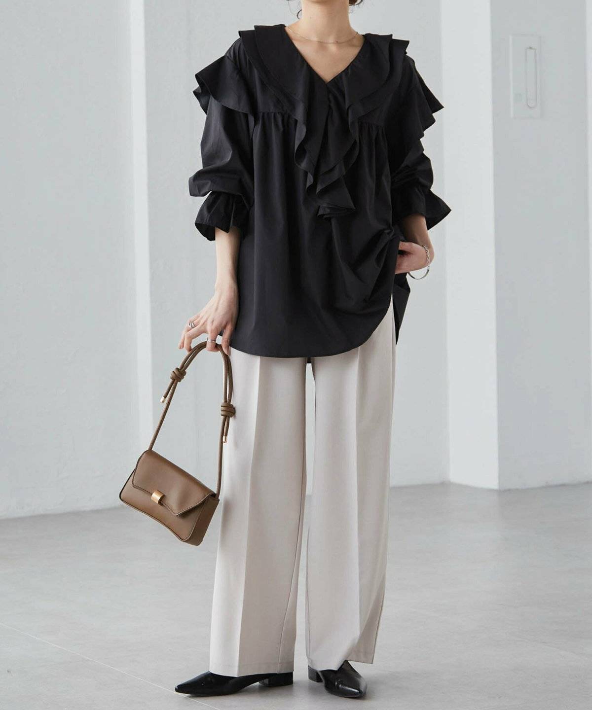 黒ブラウスにグレーのパンツを合わせた女性