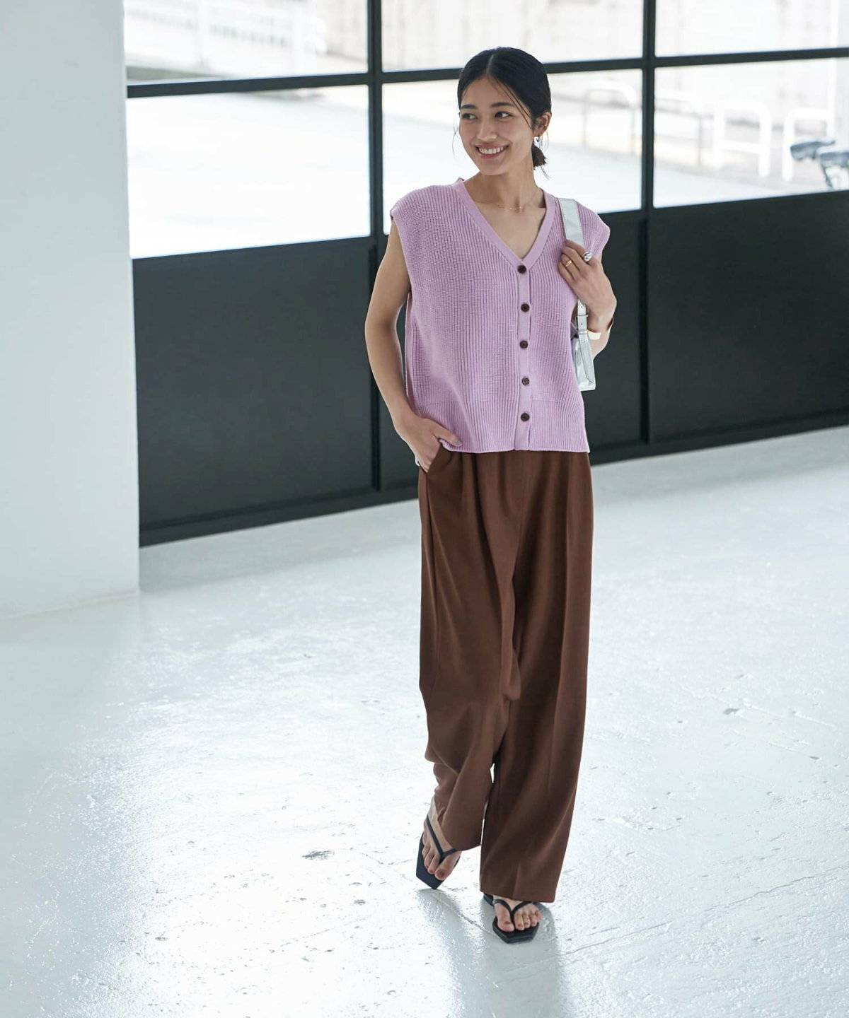 ラベンダーのニットベスト✕ブラウンのパンツの女性