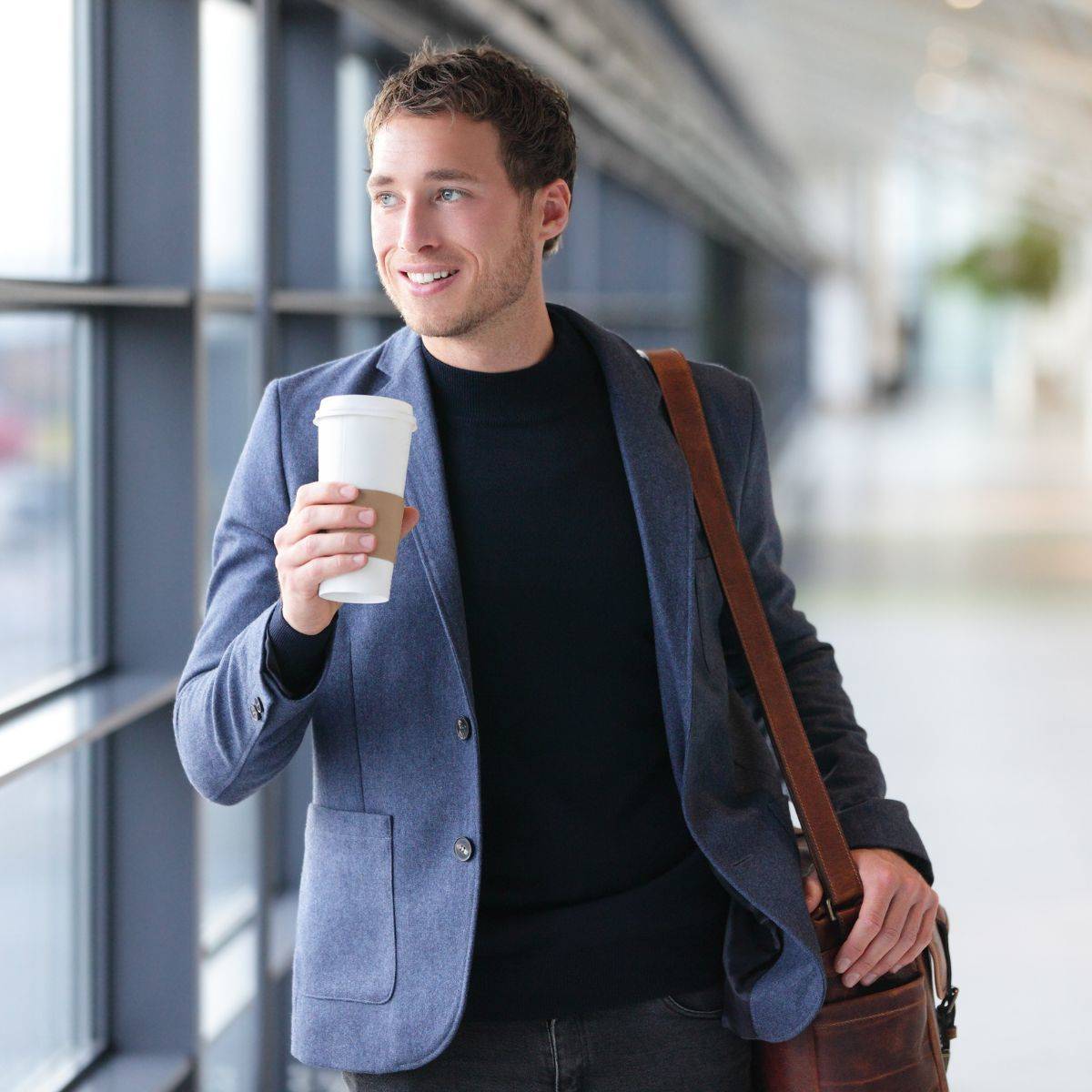 コーヒーを片手に空港を歩く男性