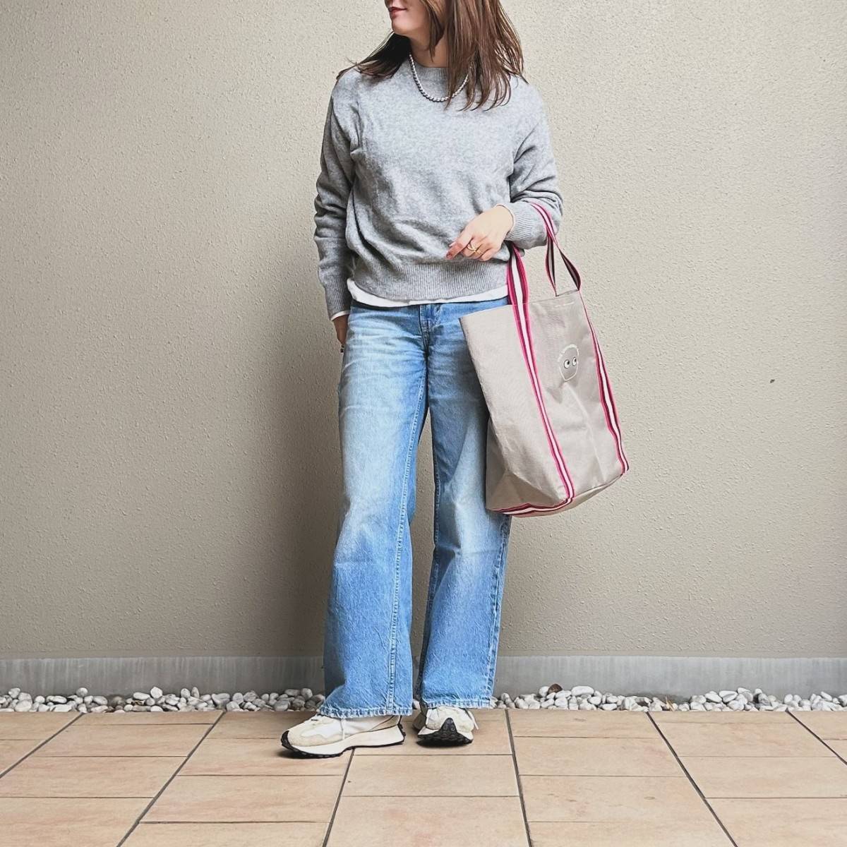 グレーのトップスにデニムパンツを合わせた女性