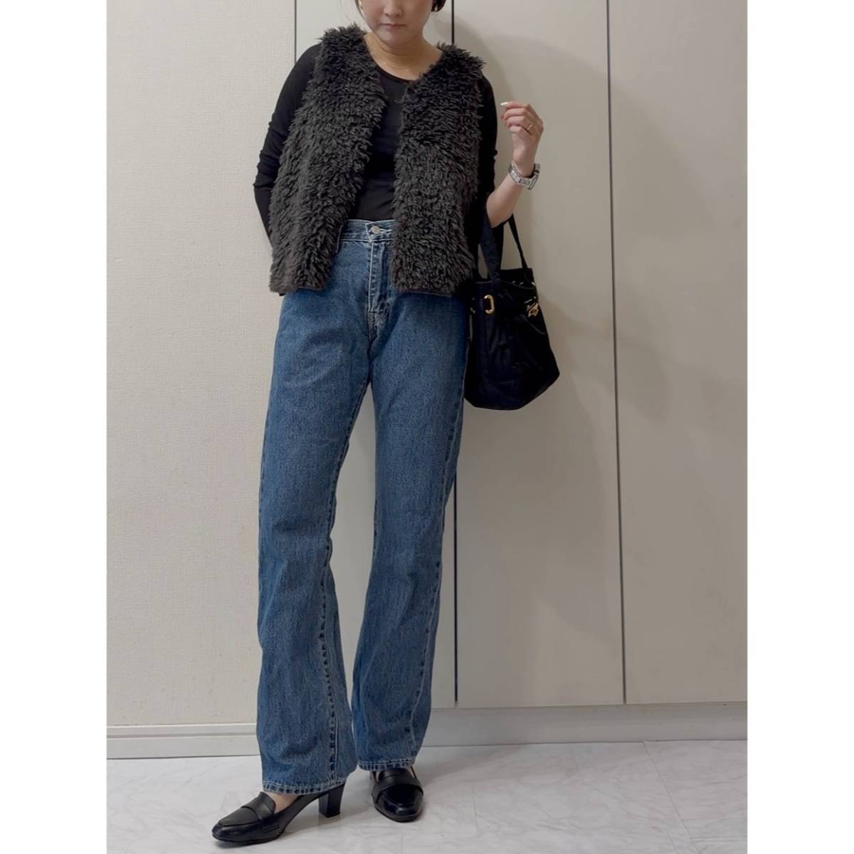 黒トップスにデニムパンツを合わせた女性