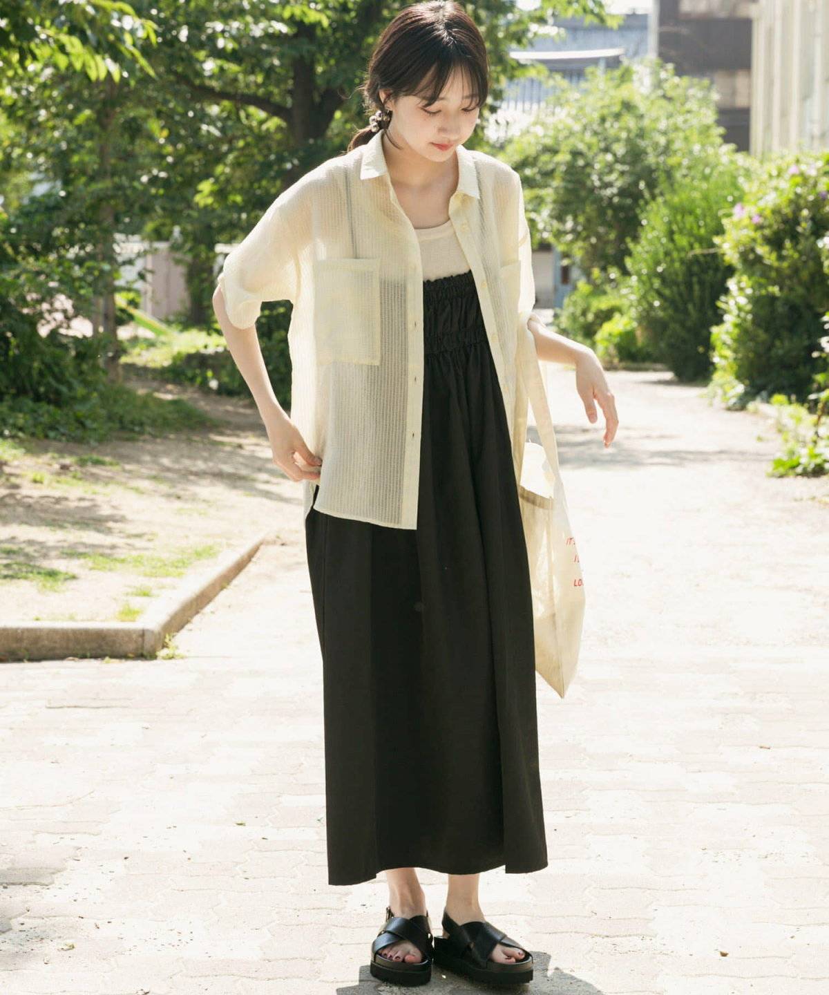 黒ワンピースにストライプ柄シャツを羽織った女性