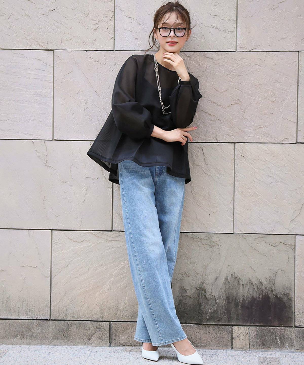 黒ブラウスにデニムを合わせた女性