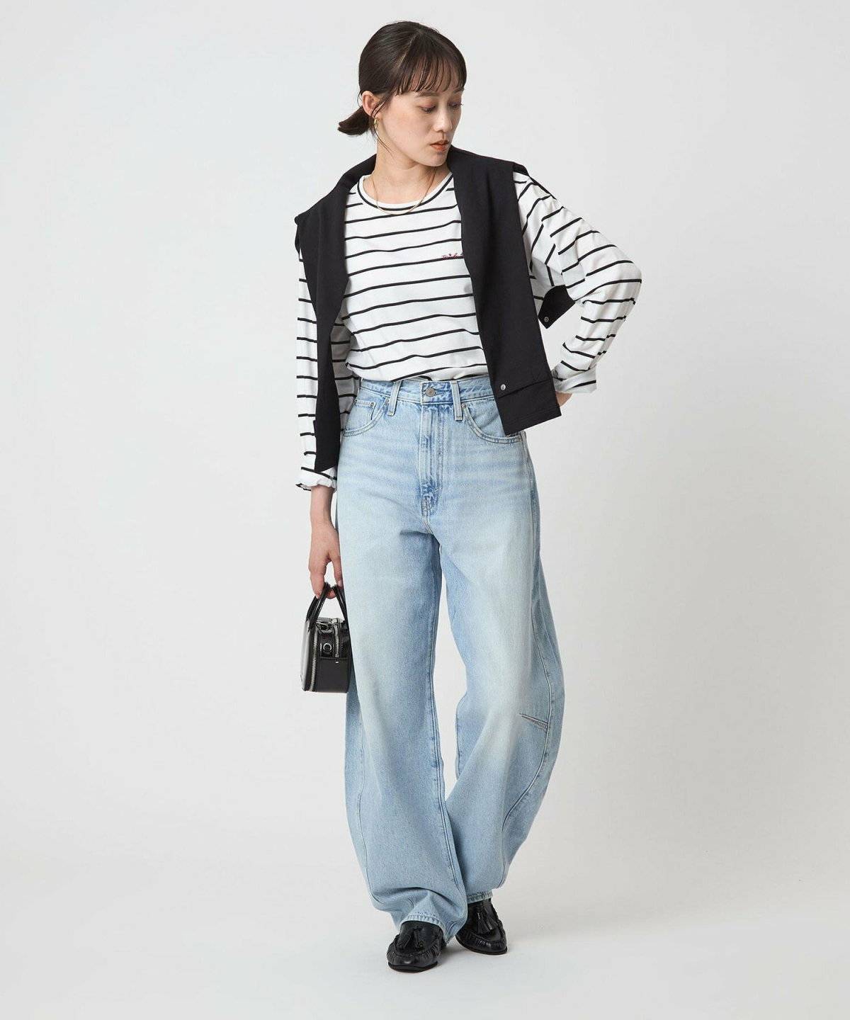 ボーダー柄トップスに黒デニムを合わせてカーディガンを肩掛けした女性