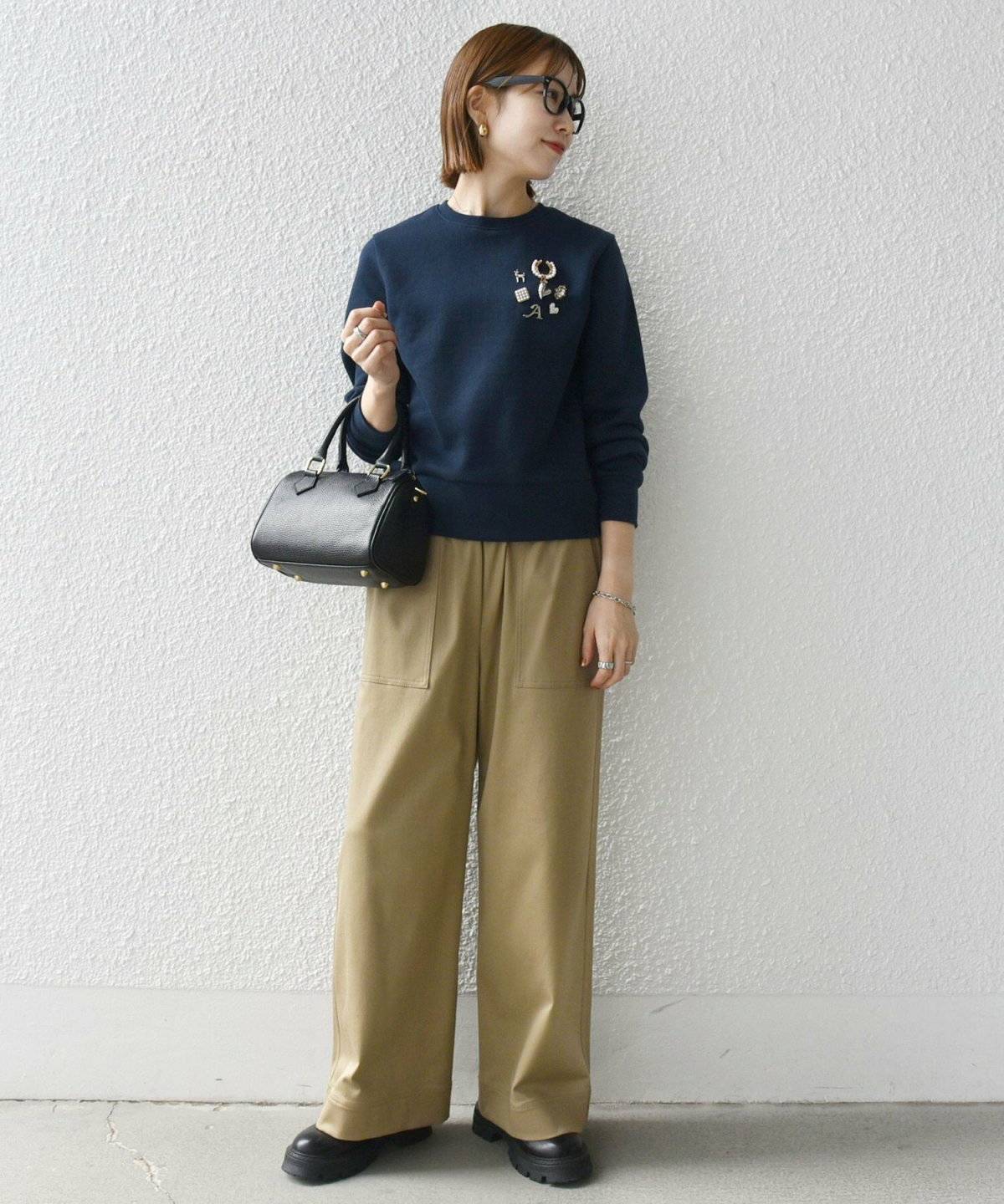 ネイビーのスウェットにカーキのパンツを合わせた女性