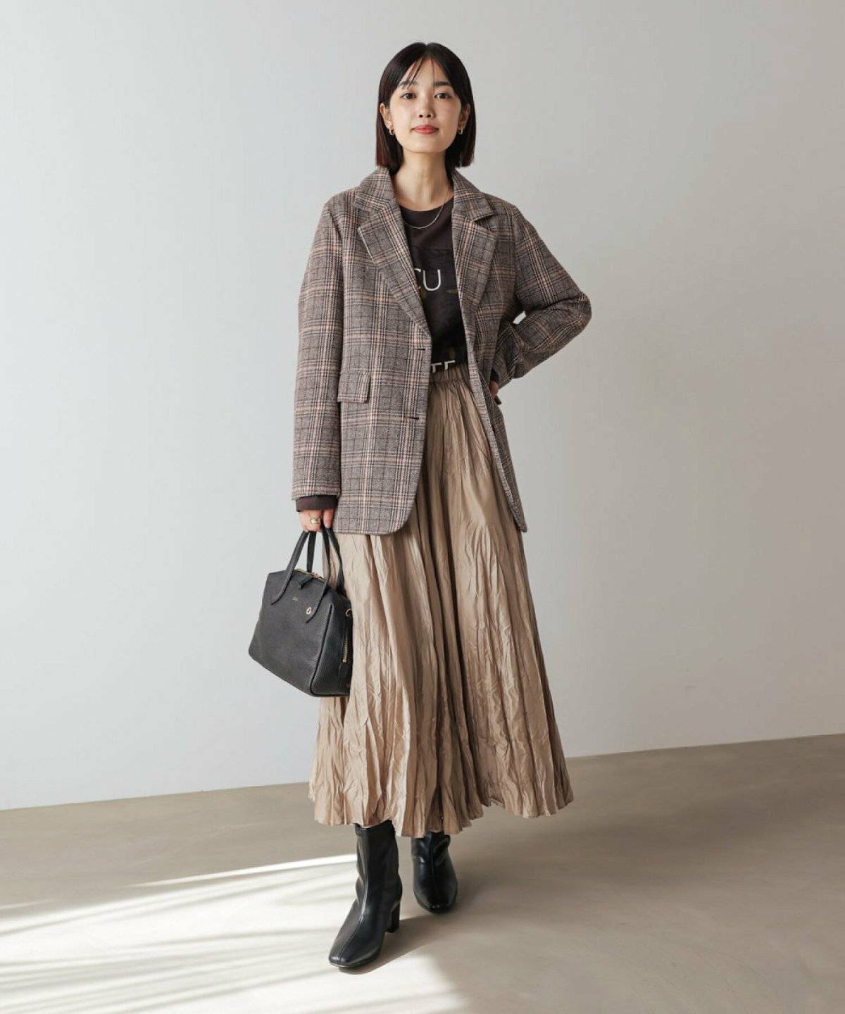 ロゴTシャツにスカートを合わせてジャケットを羽織った女性