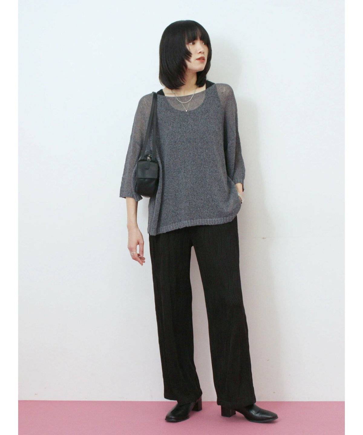 メッシュ編みニットに黒パンツを合わせた女性