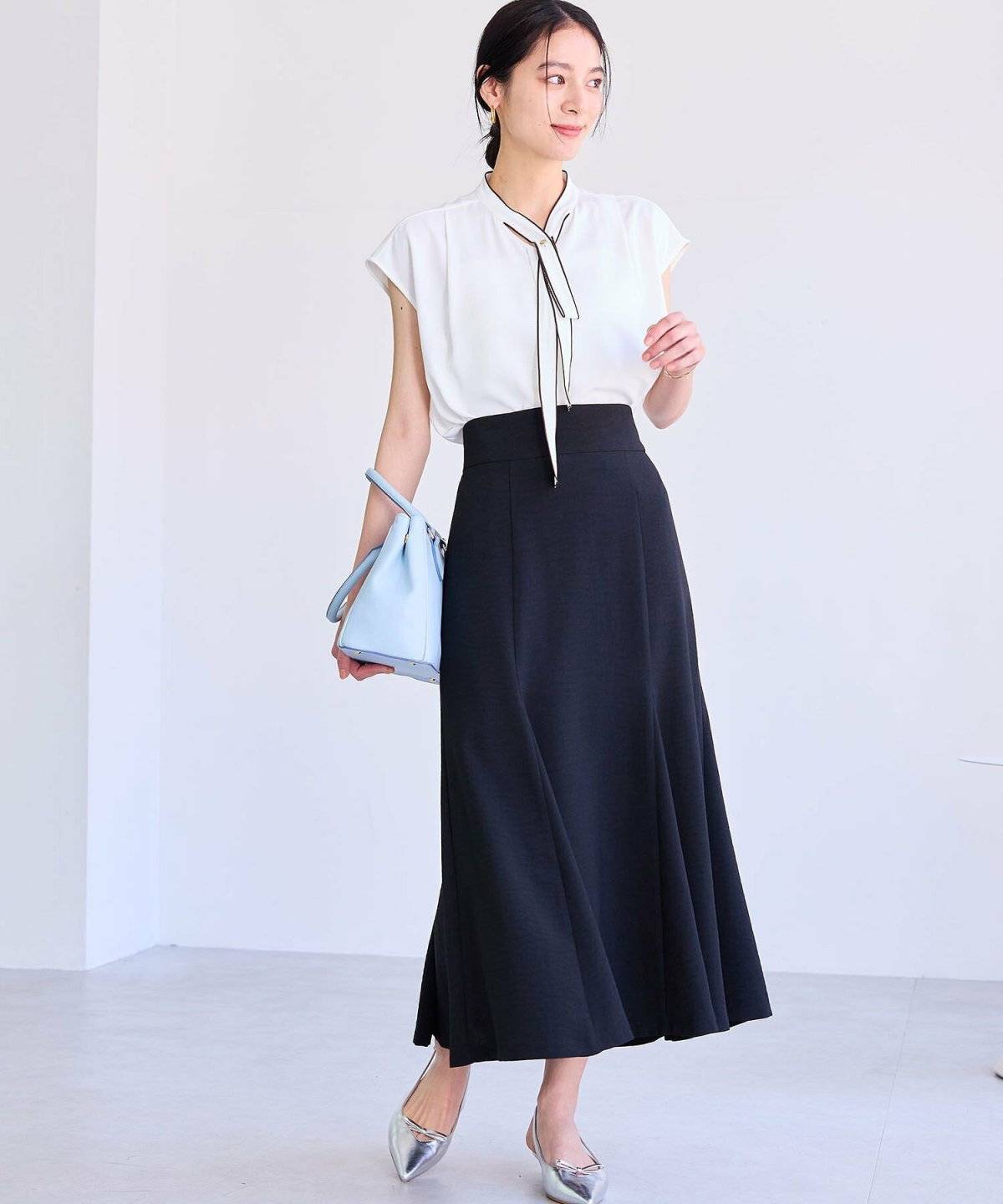 ベージュのブラウスに黒のマーメイドスカートを合わせた女性