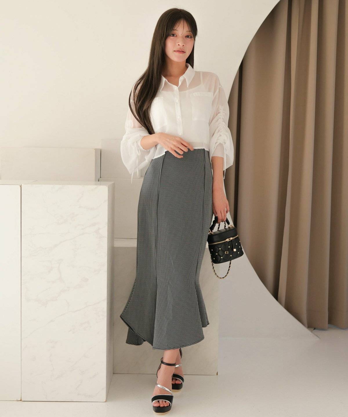 ブラウンのブラウスにギンガムチェック柄のマーメイドスカートを合わせた女性