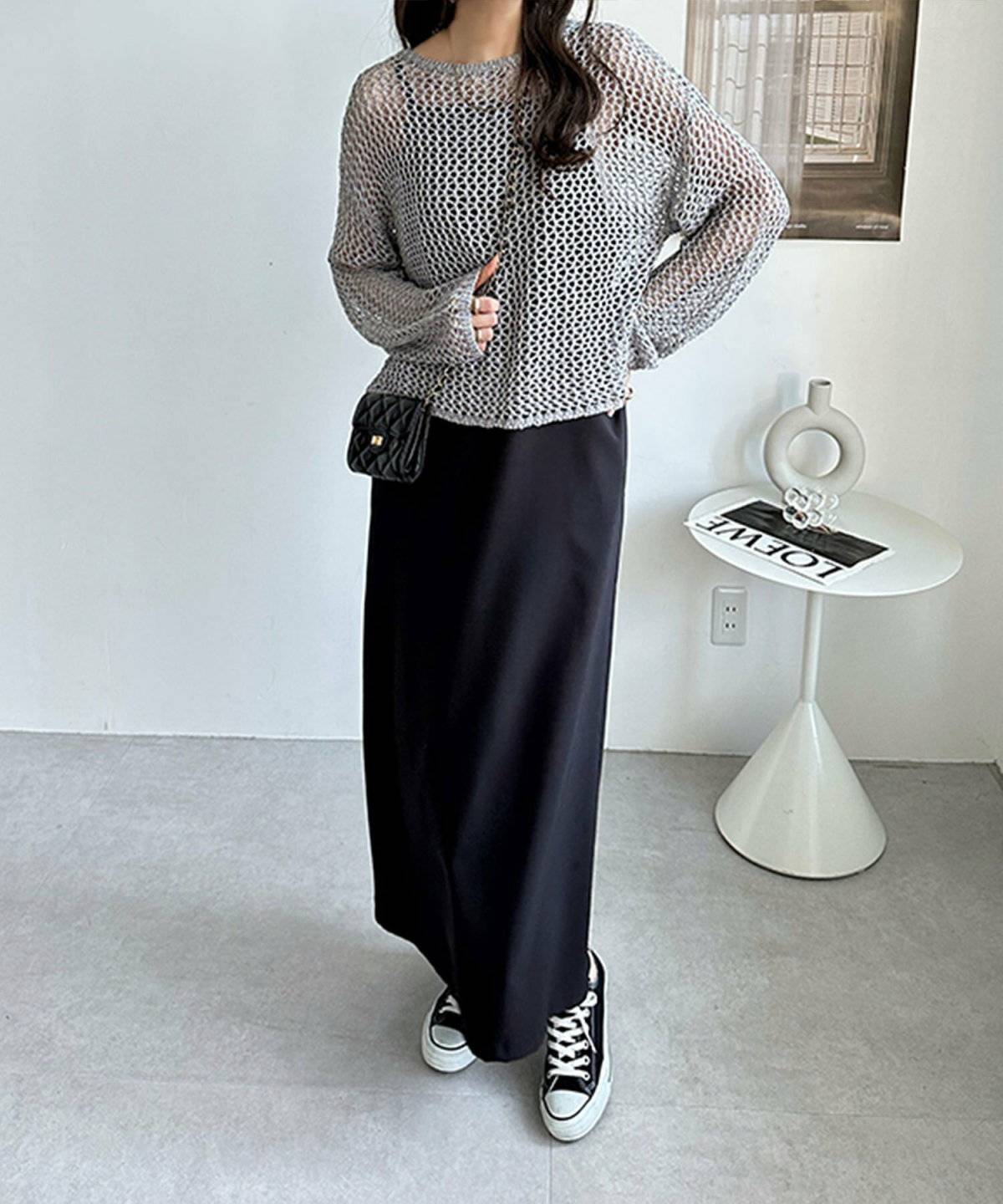 シルバーのニットに黒のマーメイドスカートを合わせた女性