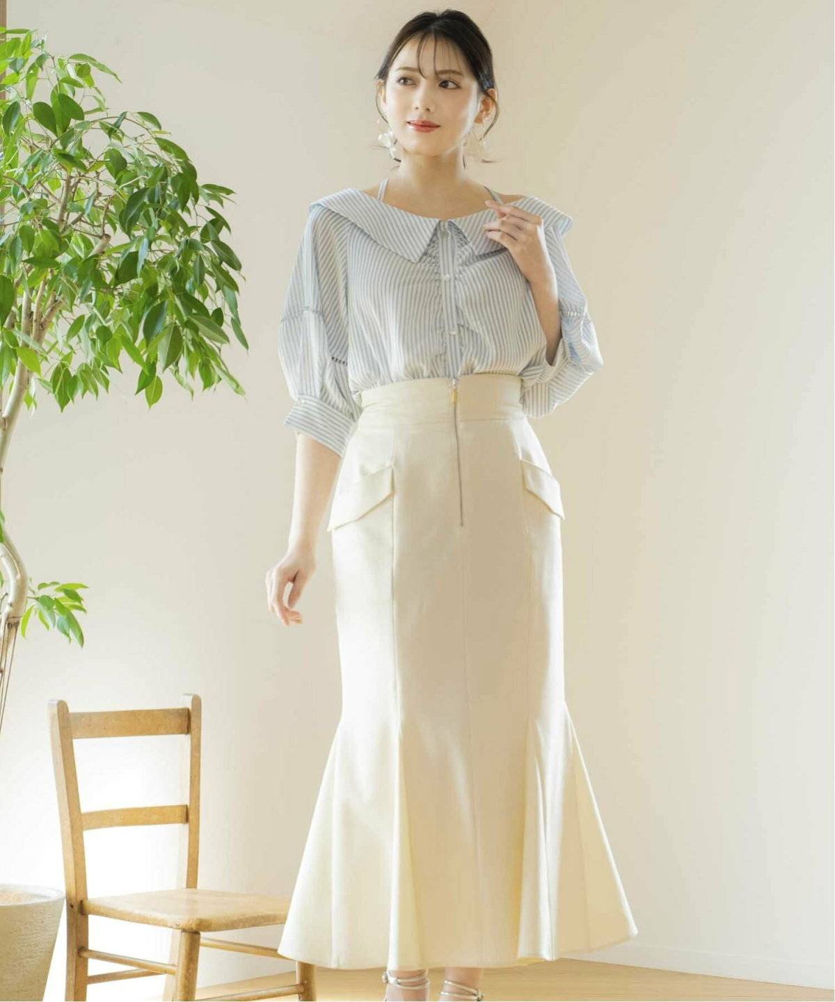 ブルーのシャツに白のマーメイドスカートを合わせた女性