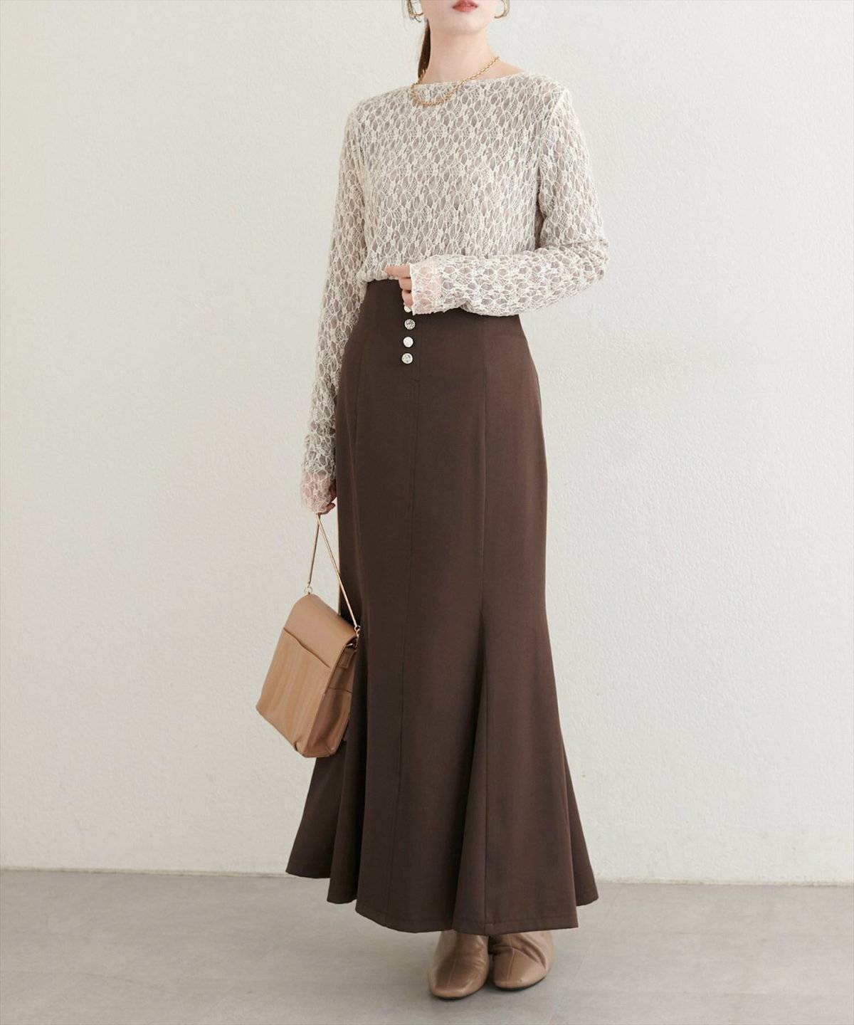 ベージュのニットにブラウンのマーメイドスカートを合わせた女性