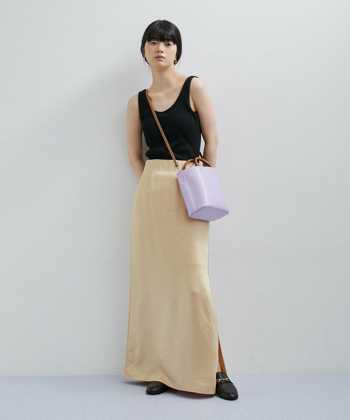 黒ニットにゴールドのマーメイドスカートを合わせた女性