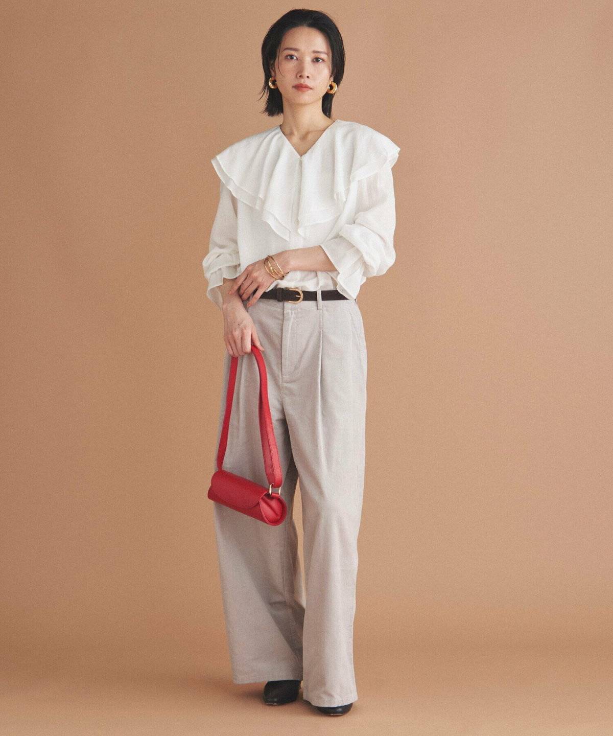 白ブラウスにベージュのパンツを合わせた女性