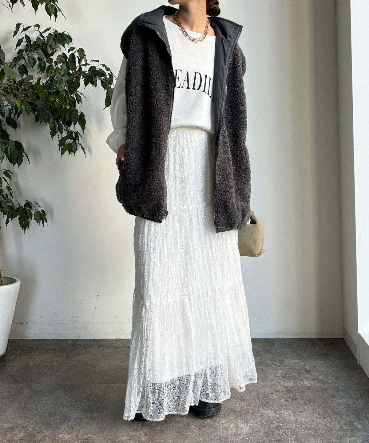 ロングTシャツにスカートを合わせてベストを重ねた女性