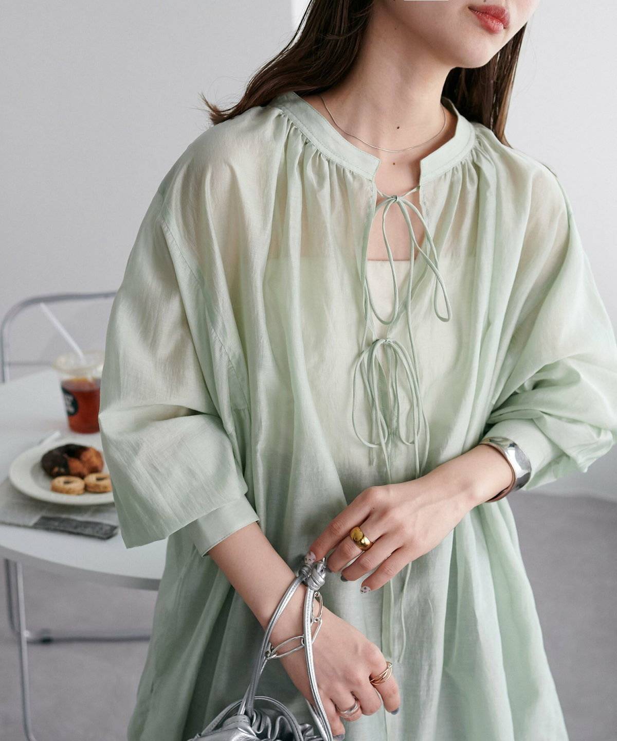 ミントグリーンプルオーバー✕ブラウンスカートの女性