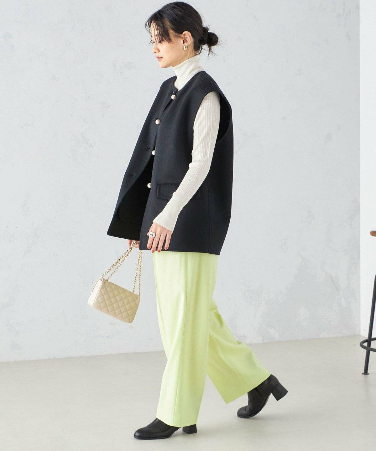ミントグリーンのストレッチパンツ✕黒ベストの女性