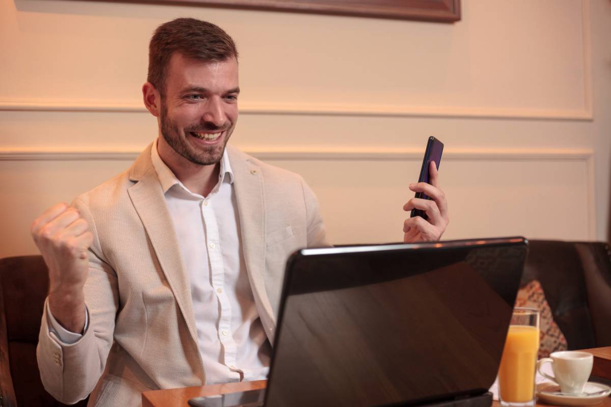 パソコンを見ながらガッツポーズする男性