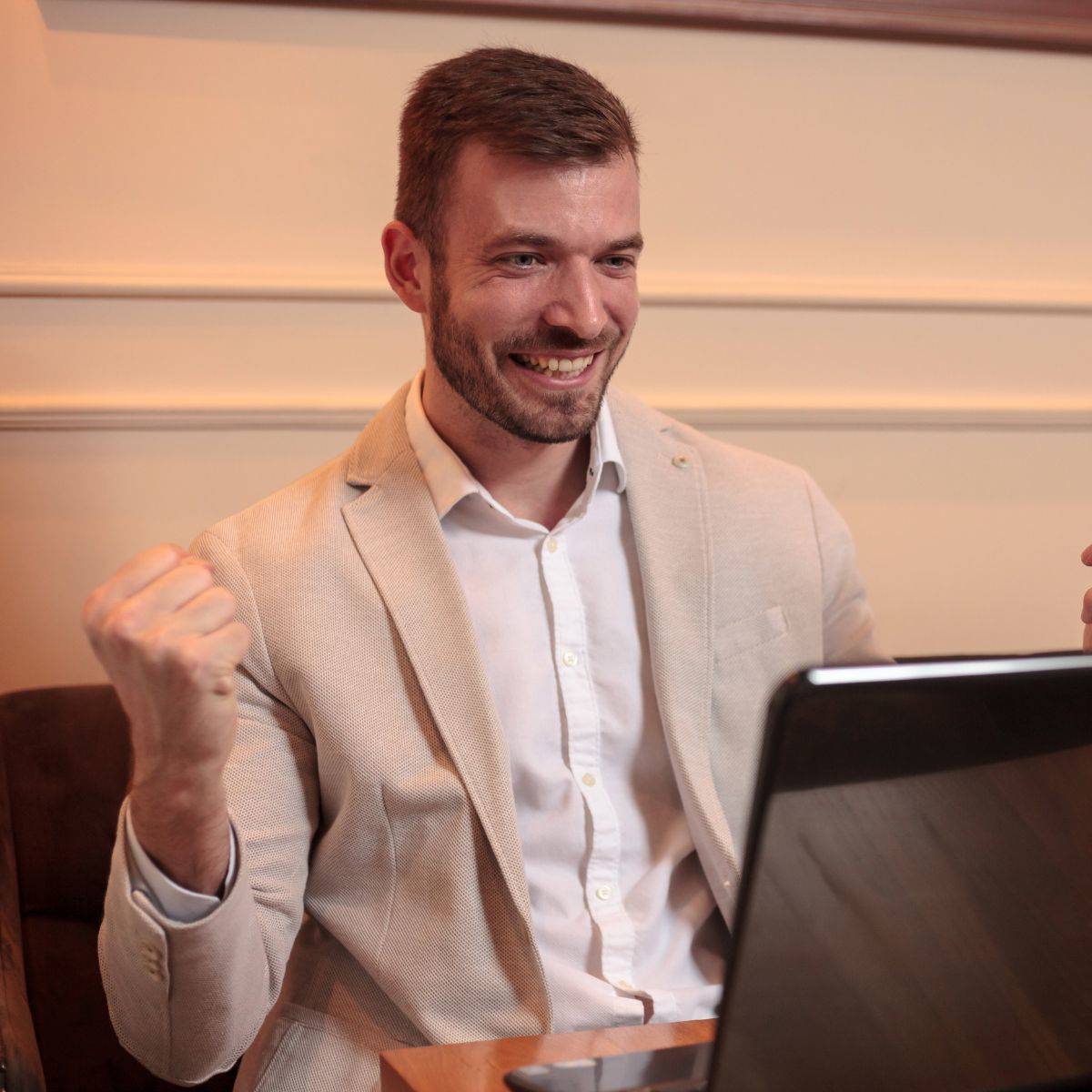 パソコンを見ながらガッツポーズする男性