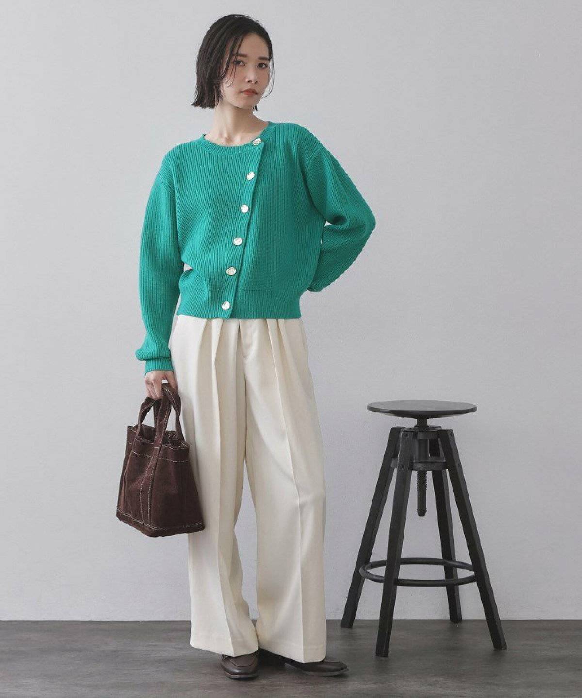 グリーンのカーディガンに白パンツを合わせた女性