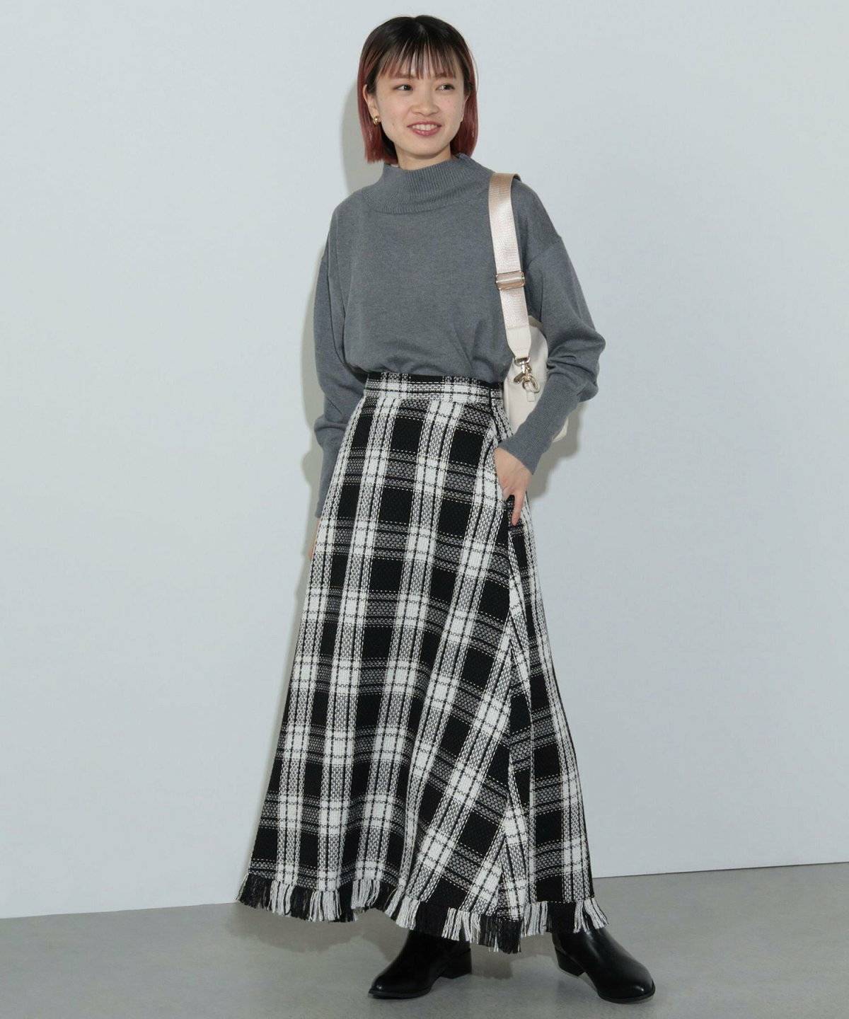グレーのトップスにチェック柄スカートを合わせた女性