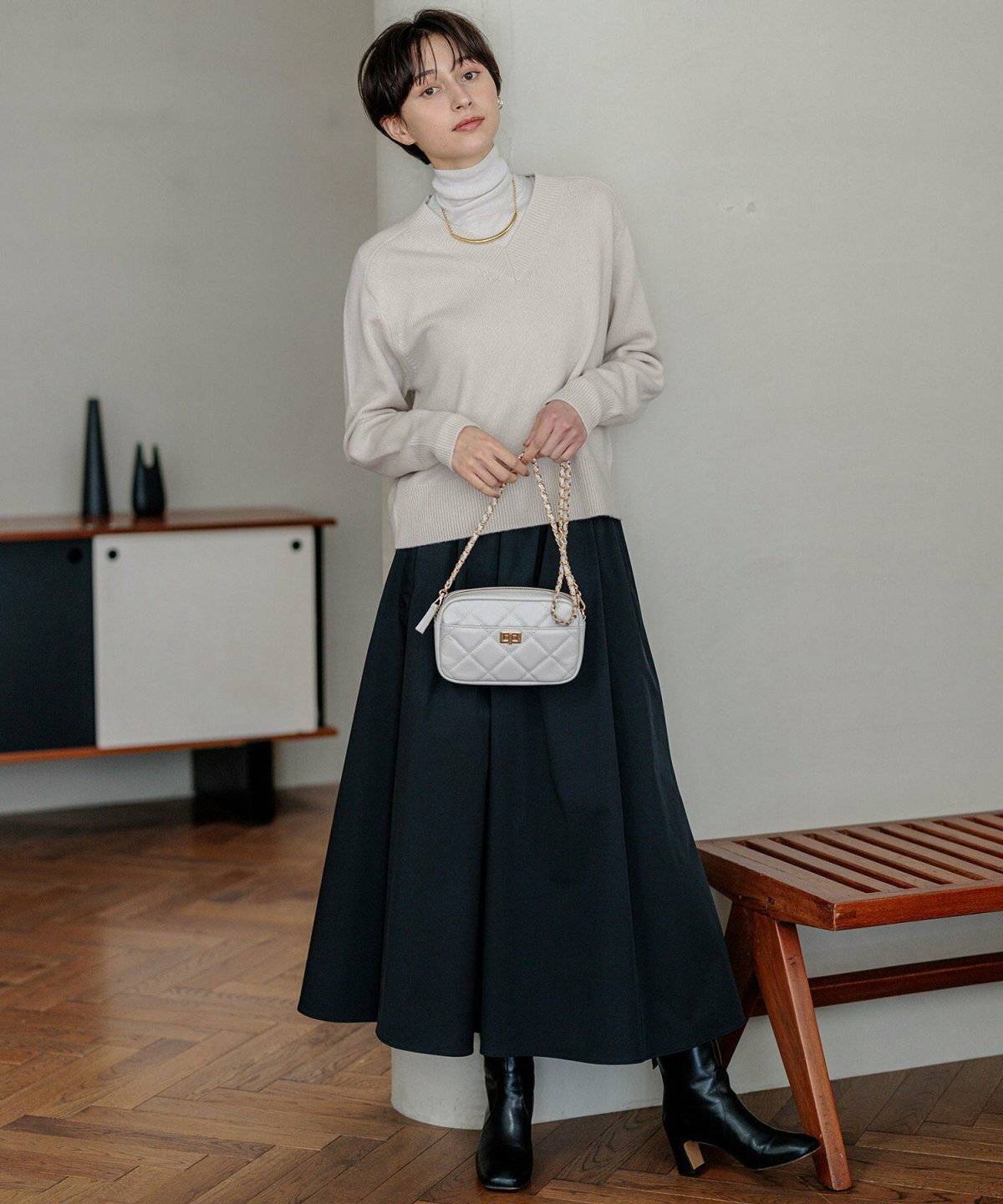 ベージュのニットに白スカートを合わせた女性