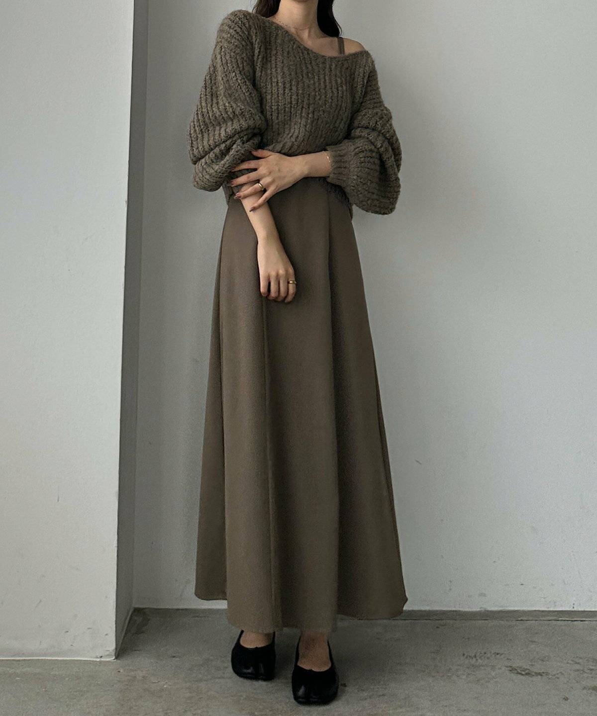 ワンピースにベージュのニットを重ねた女性