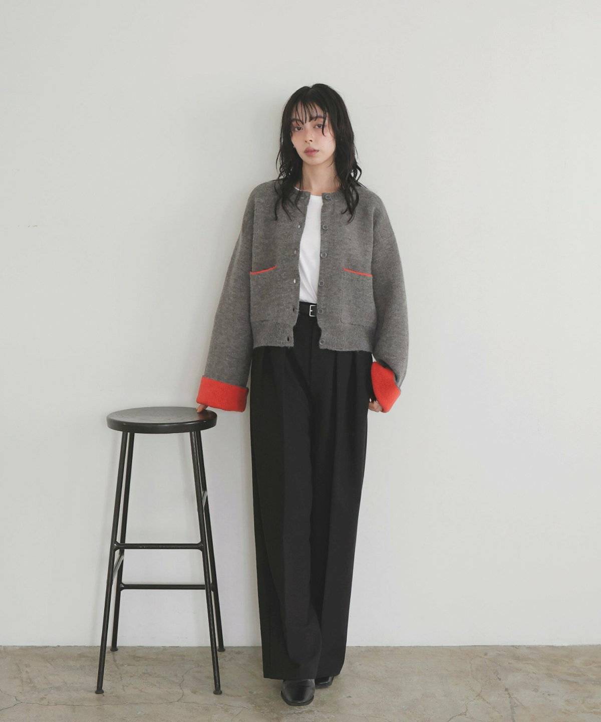 グレーのカーディガンに黒パンツを合わせた女性