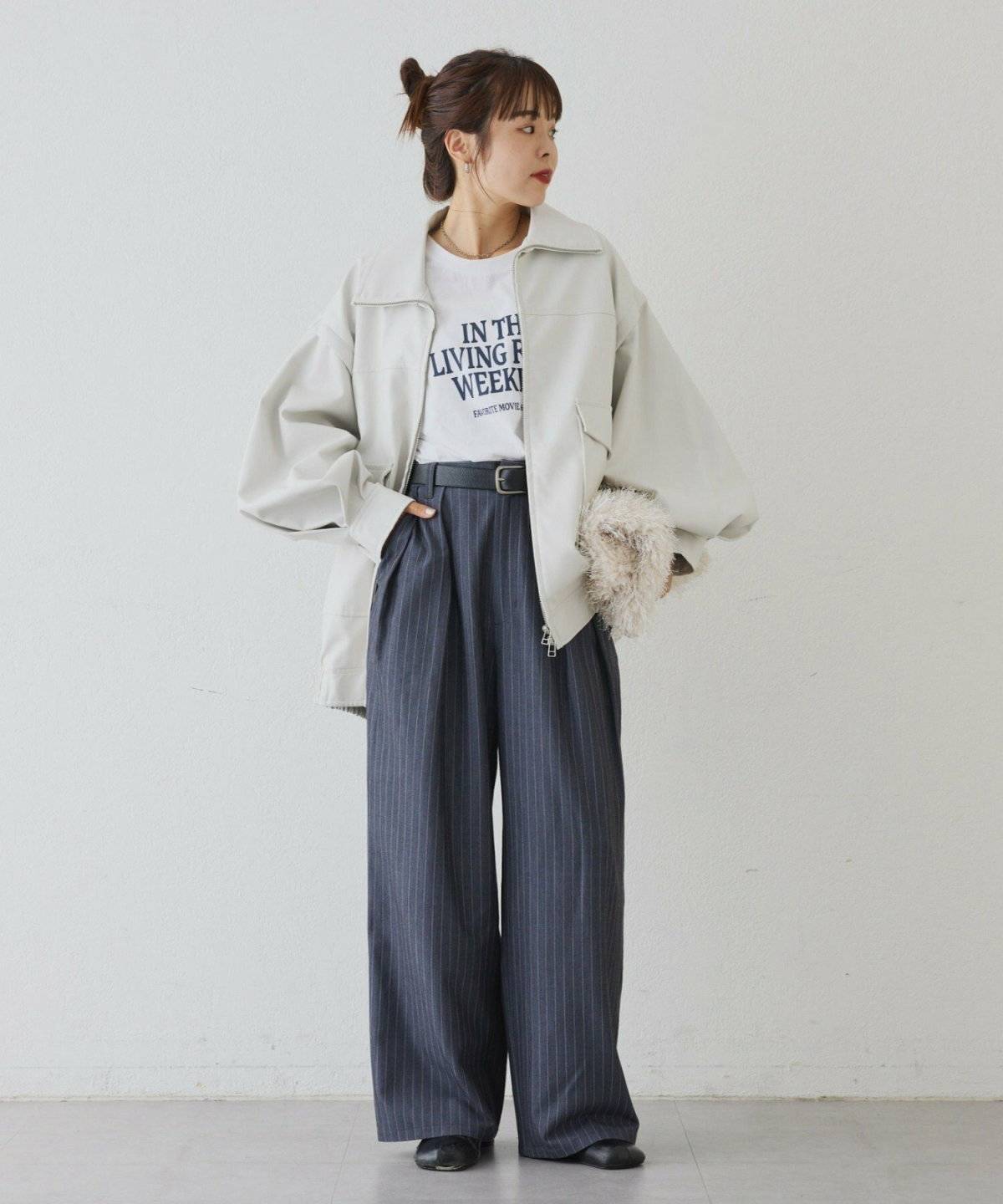 白のレザージャケットにグレーのパンツを合わせた女性