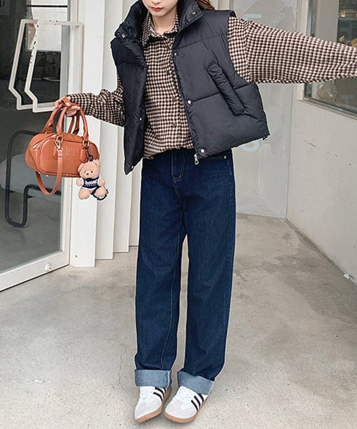 シャギーチェック柄シャツにダウンベストを重ねてデニムを合わせた女性