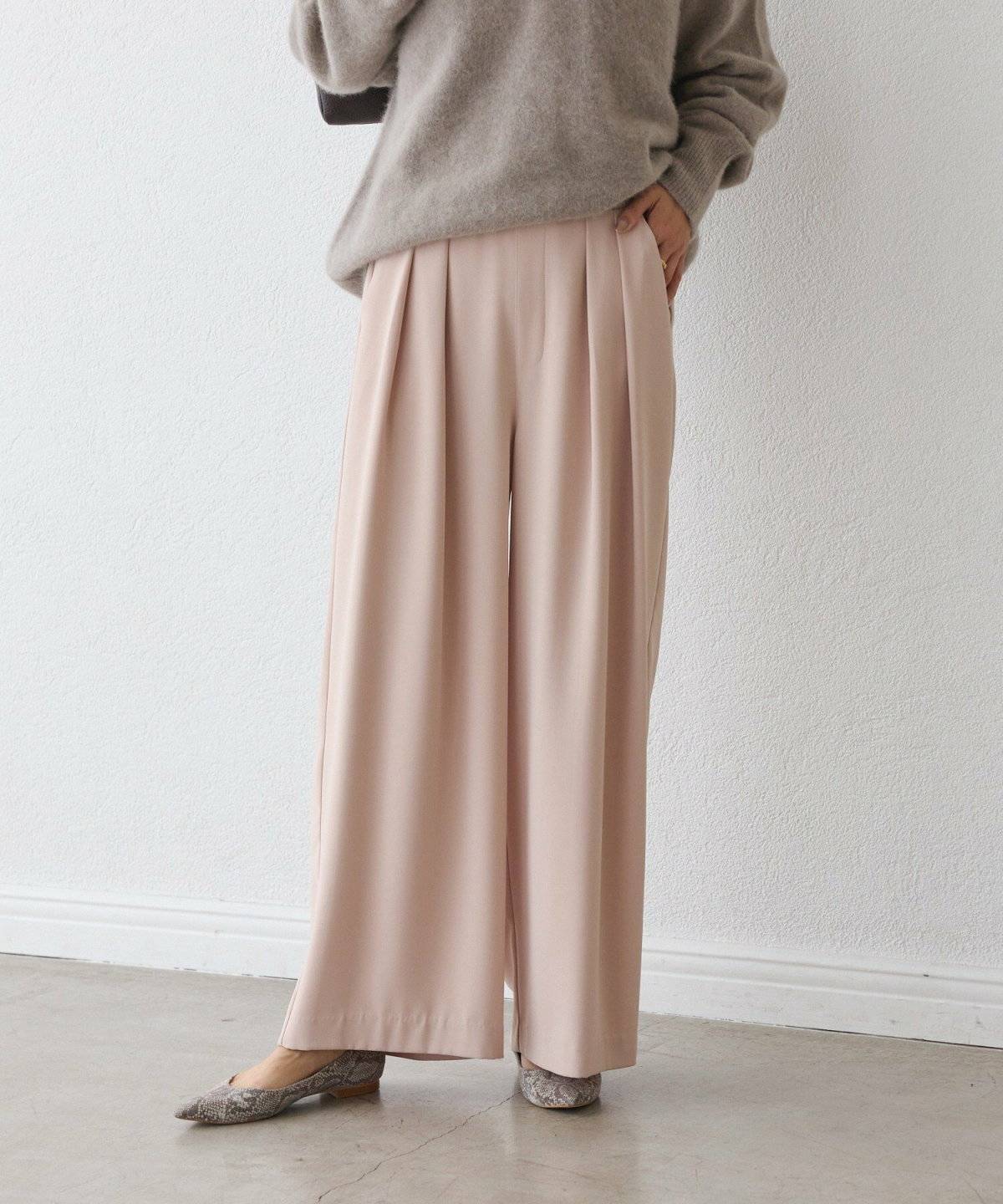 ベージュのニットにピンクのパンツを合わせた女性