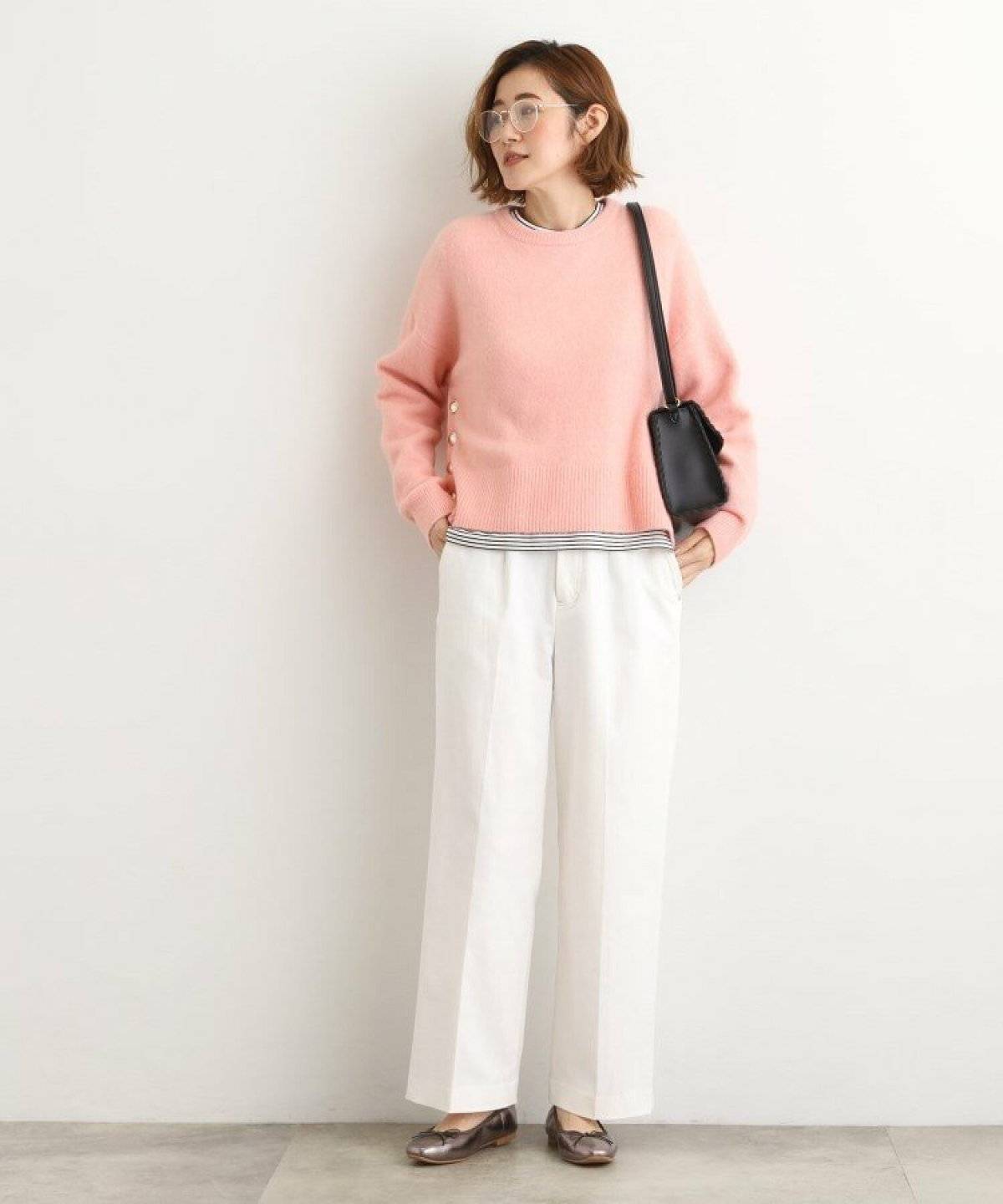 ピンクのニットに白デニムを合わせた女性