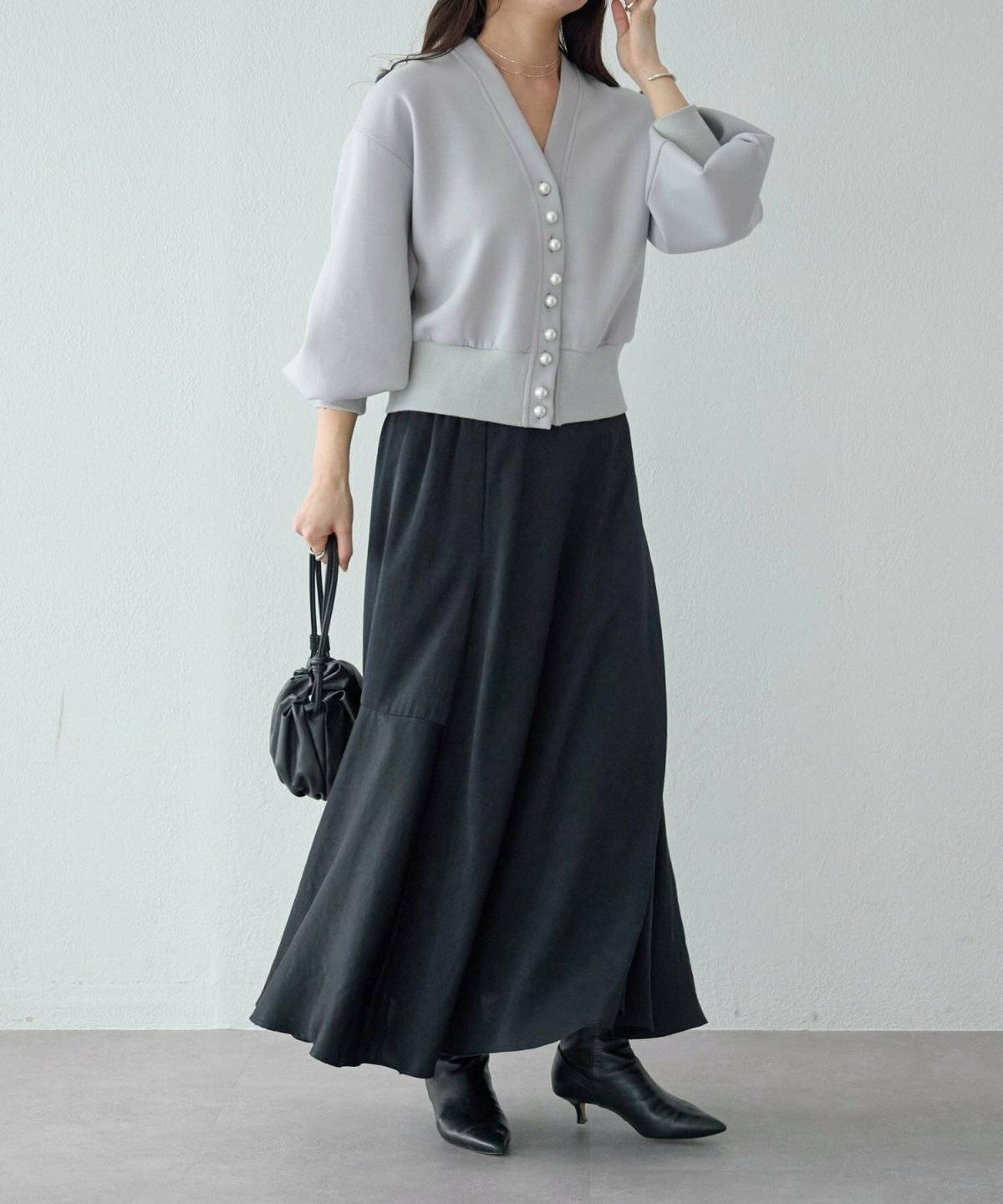 グレーのカーディガンに黒スカートを合わせた女性