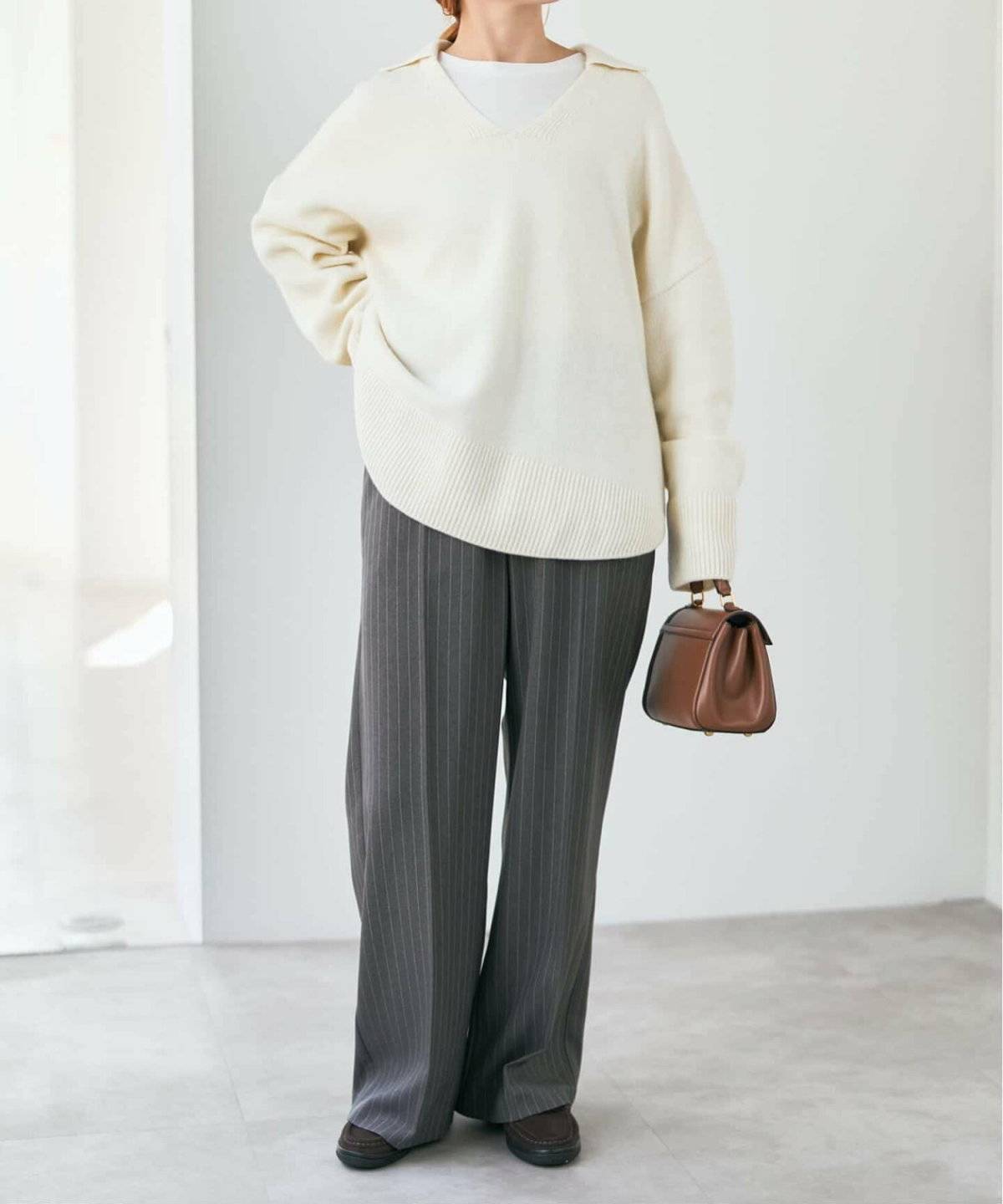 白ニットにグレーのパンツを合わせた女性
