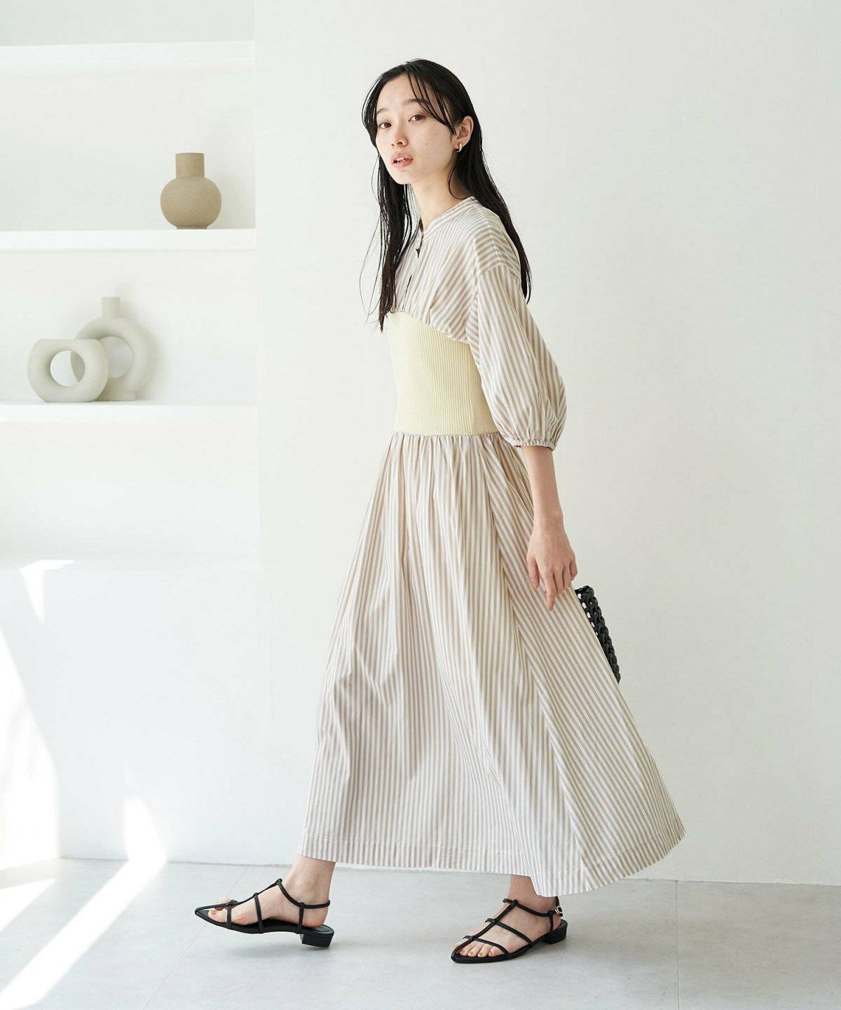 ストライプ柄のシャツワンピースにビスチェを重ねた女性