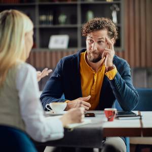  同僚の女性の話を聞く男性 