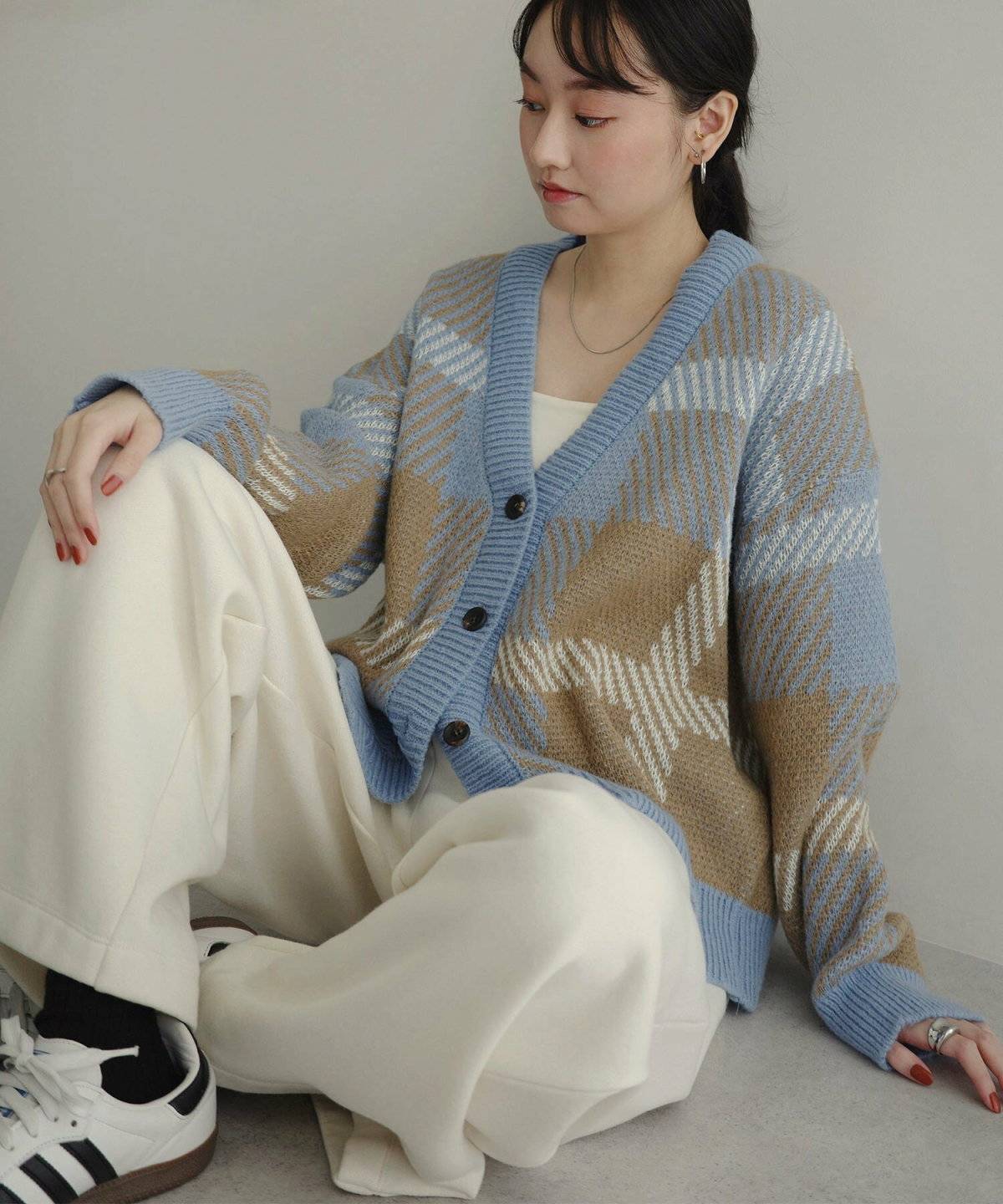 ベージュのカーディガンに白パンツを合わせた女性