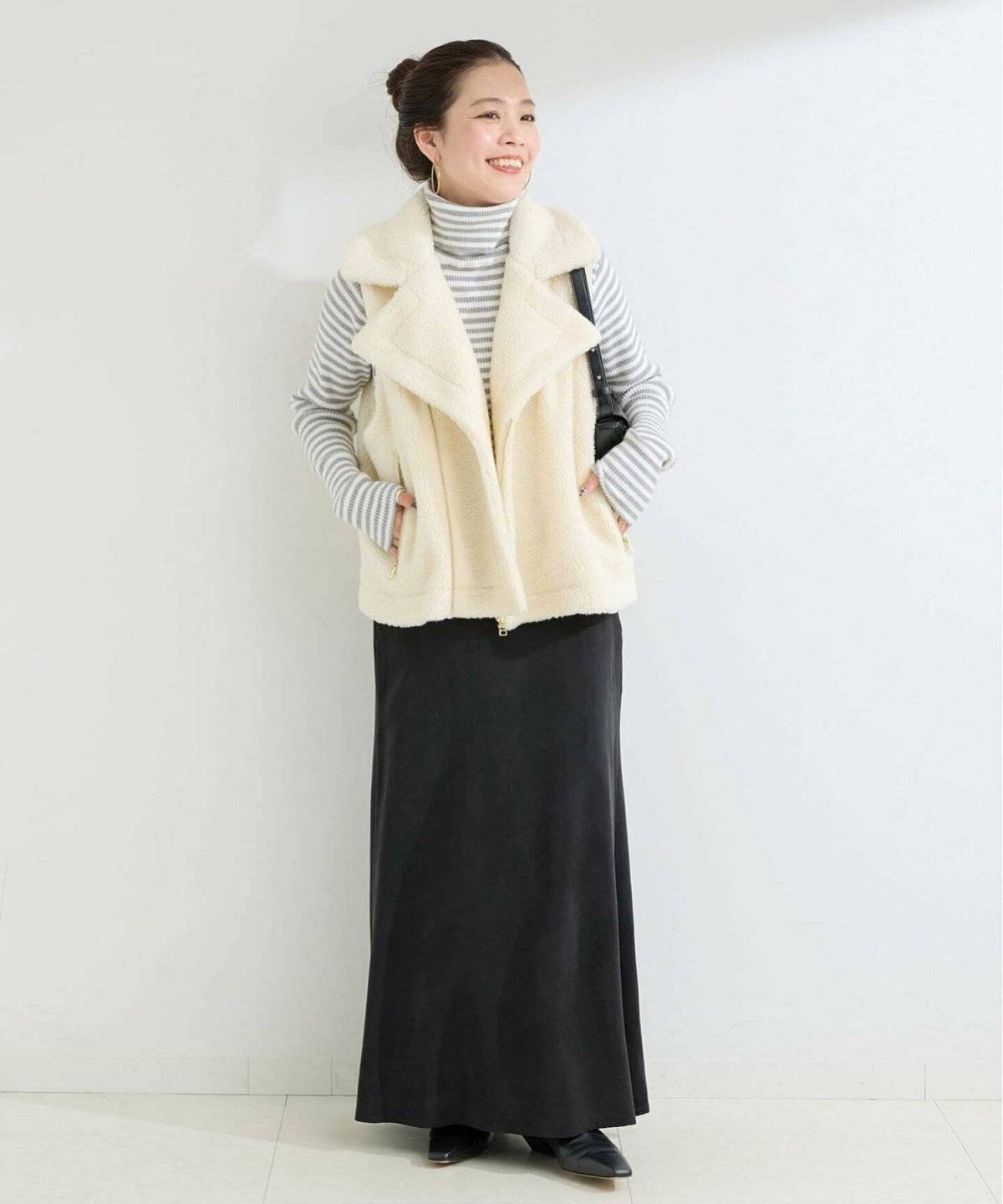 ボーダー柄トップスにベストを重ねた女性