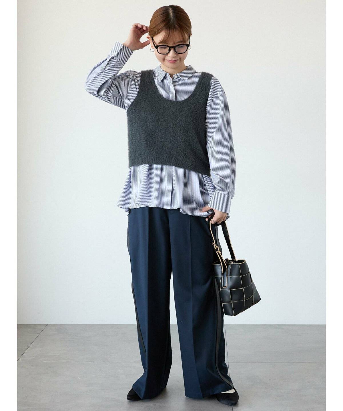 ストライプ柄シャツにビスチェを重ねてパンツを合わせた女性