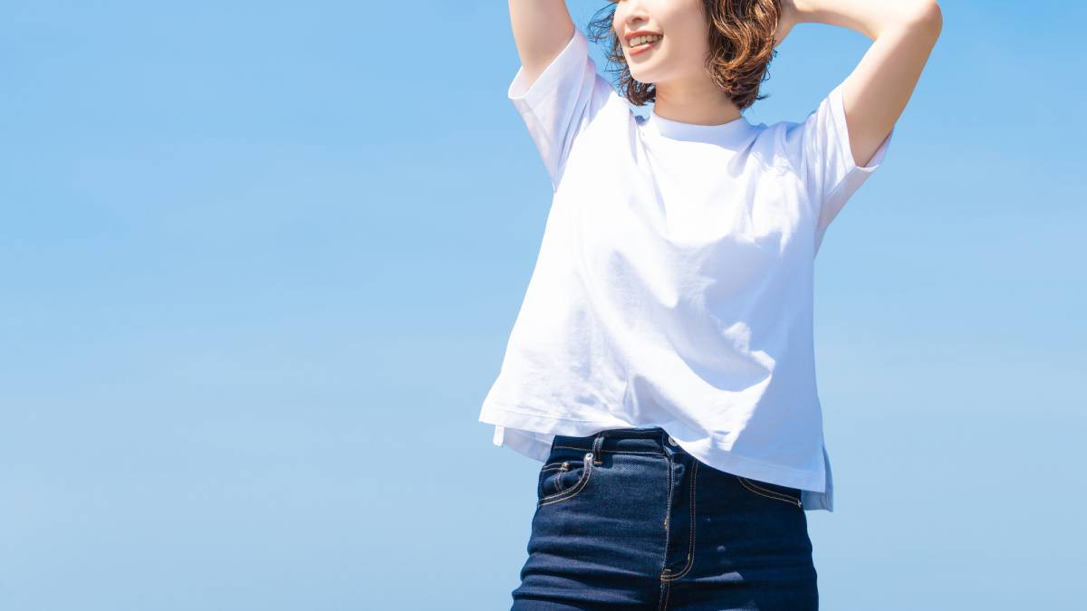 夏の青空と白いTシャツを着た笑顔の女性