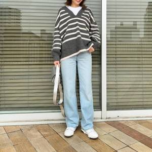  ボーダー柄のニットにデニムパンツを合わせた女性 