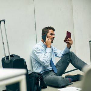  パスポートを見ながら電話する男性 