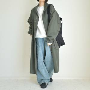  カーキのコートにデニムパンツを合わせた女性 