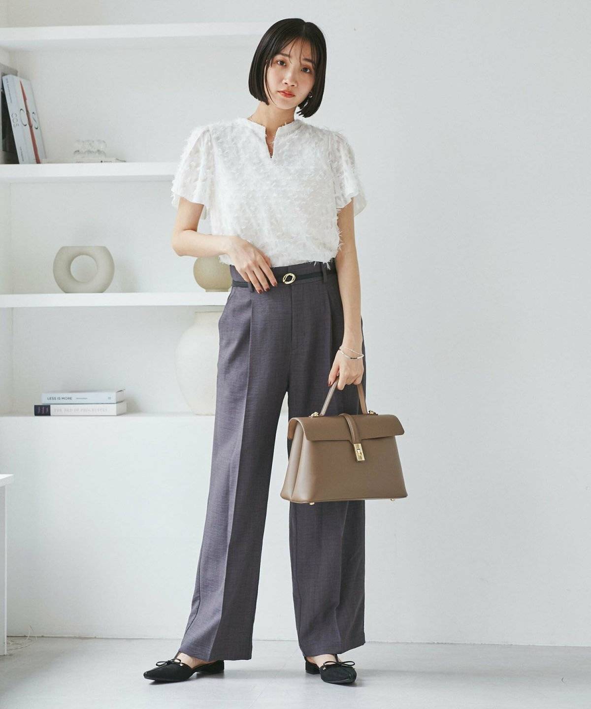 白ブラウスにグレーのパンツを合わせた女性