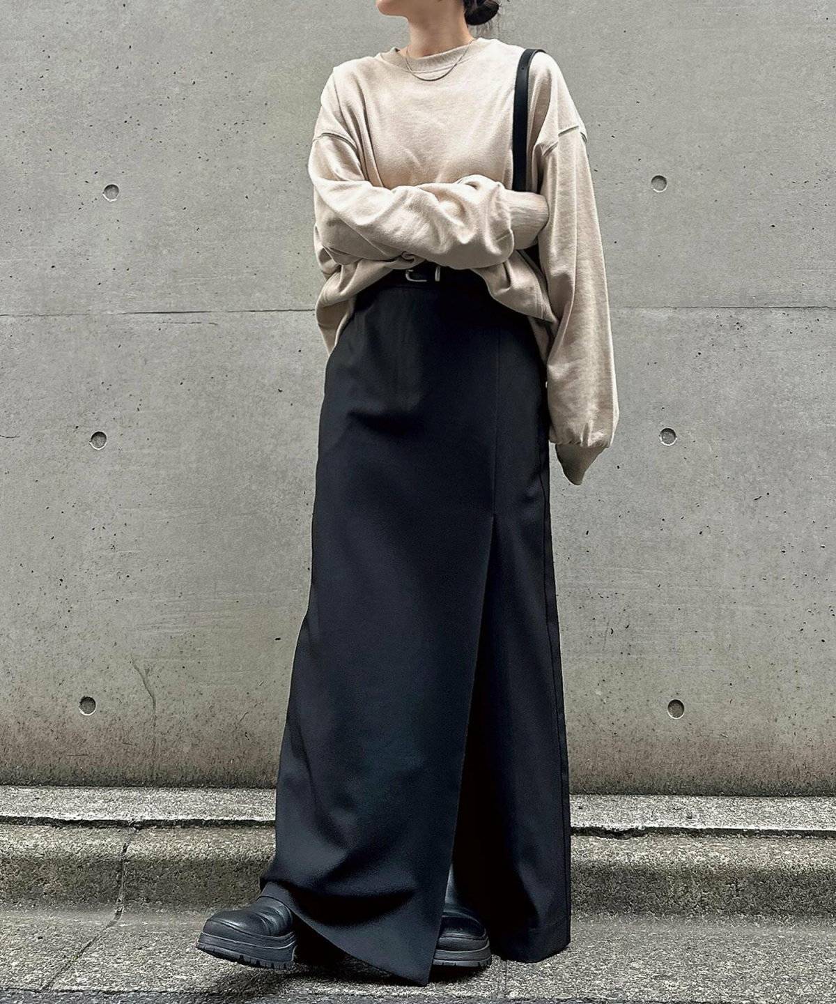 ベージュのスウェットに黒スカートを合わせた女性