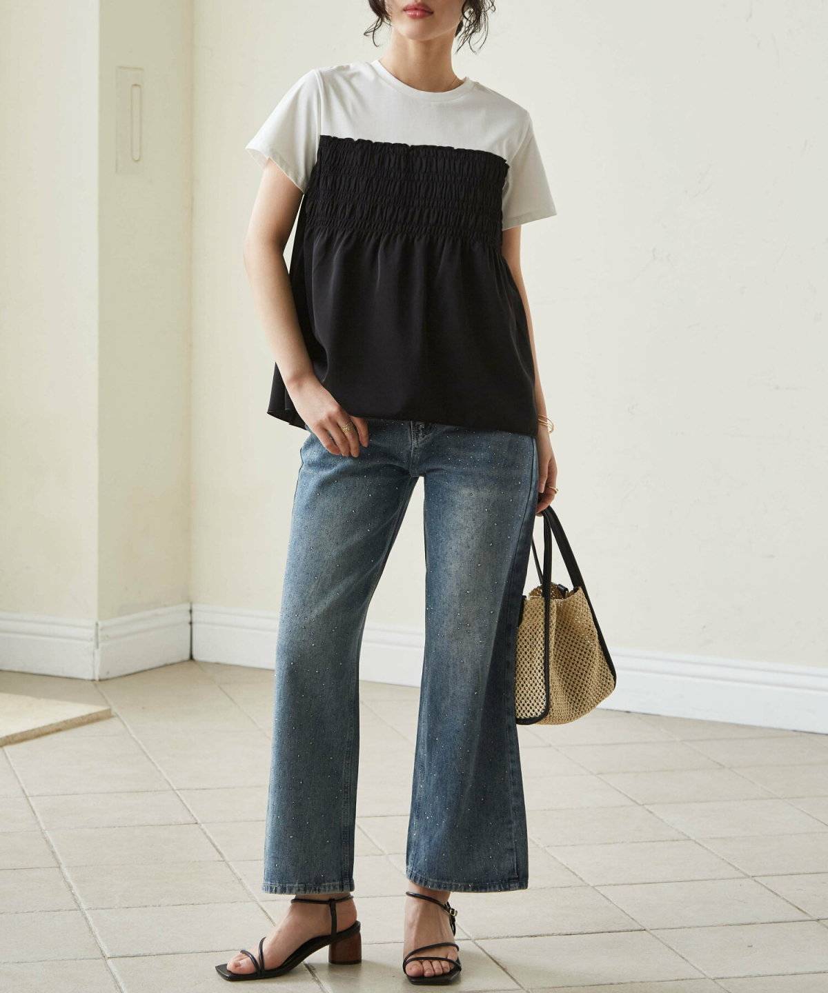 Tシャツにビスチェを重ねてデニムを穿いた女性