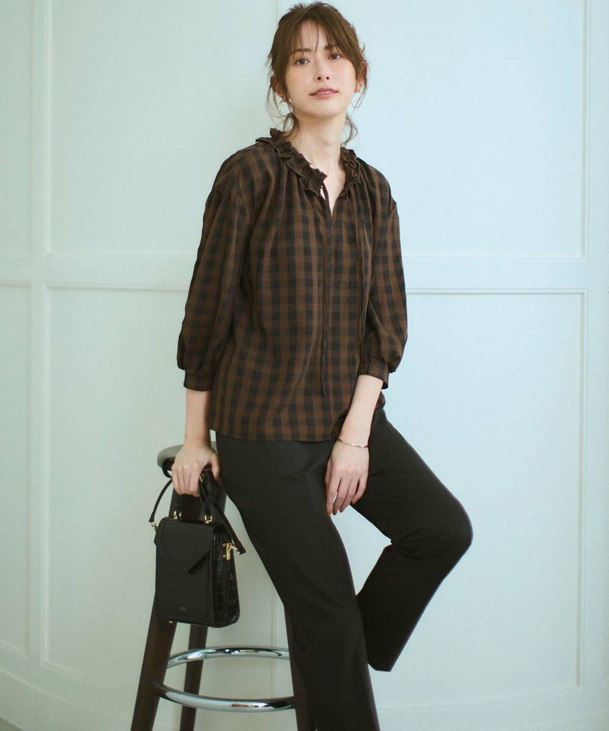 ブラウンのブラウスに黒パンツを合わせた女性