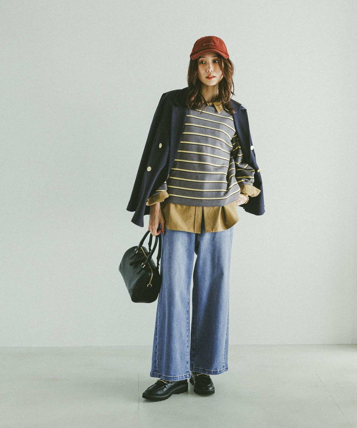 ポロシャツにデニムを合わせてネイビーのブレザーを肩掛けした女性