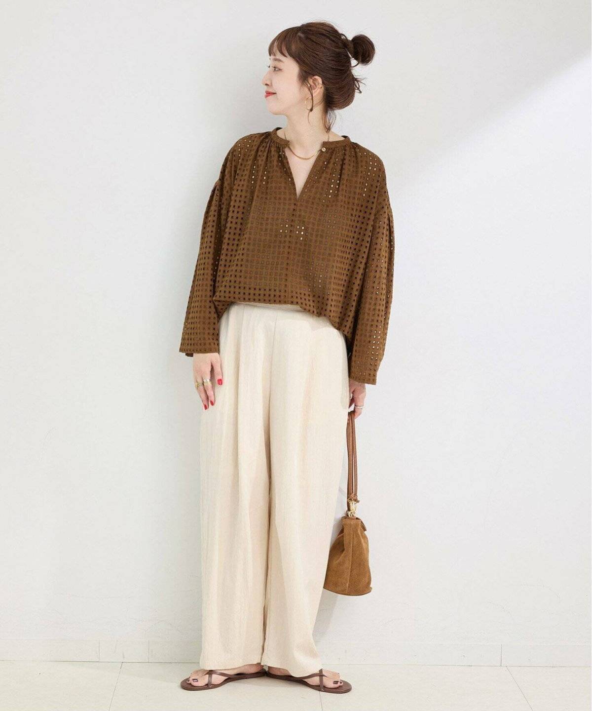 ブラウンのブラウスにベージュのパンツを合わせた女性