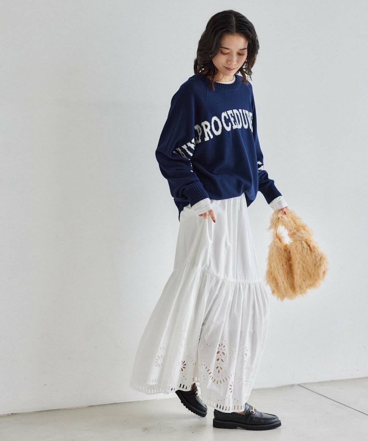ブルーのスウェットに白のスカートを合わせた女性